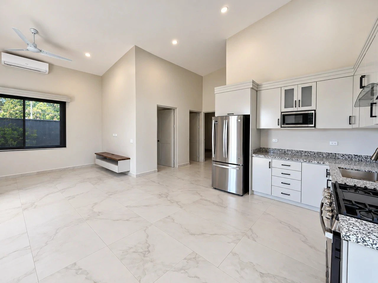 Bright open-plan kitchen and living area with marble-look floors, white cabinetry and stainless steel appliances